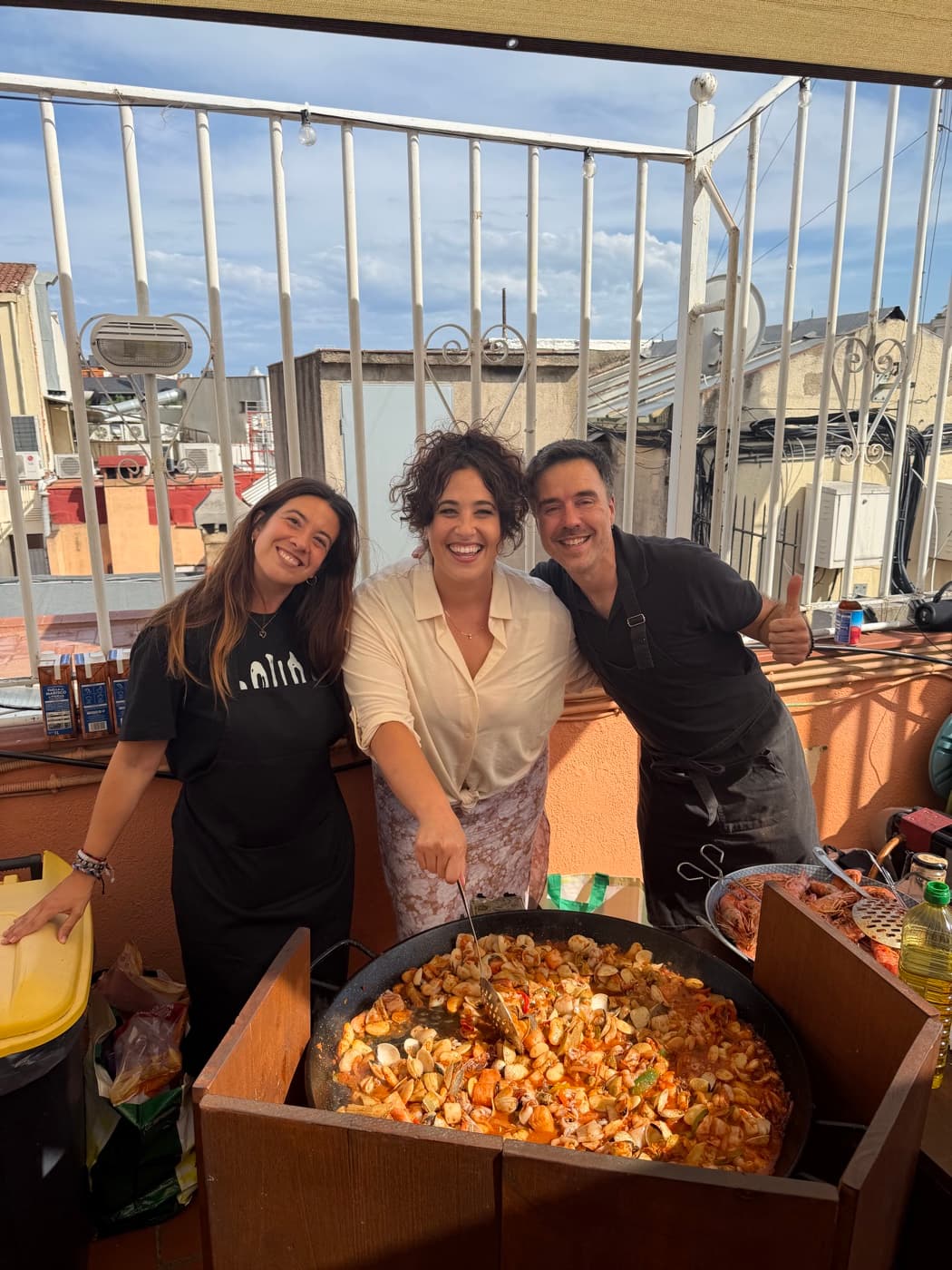 Jenna and friends around a rooftop paella in Spain