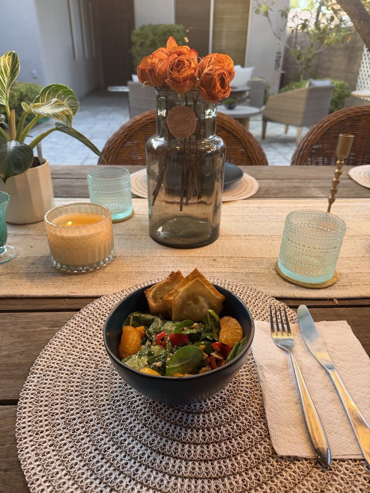 Spinach and mandarin salad with crispy wontons on a styled patio table